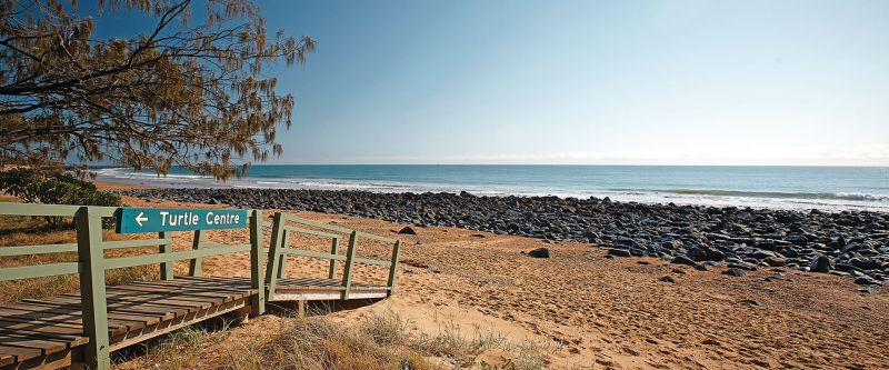 A photo of Mon Repos beach with a sign to the Turtle Centre.