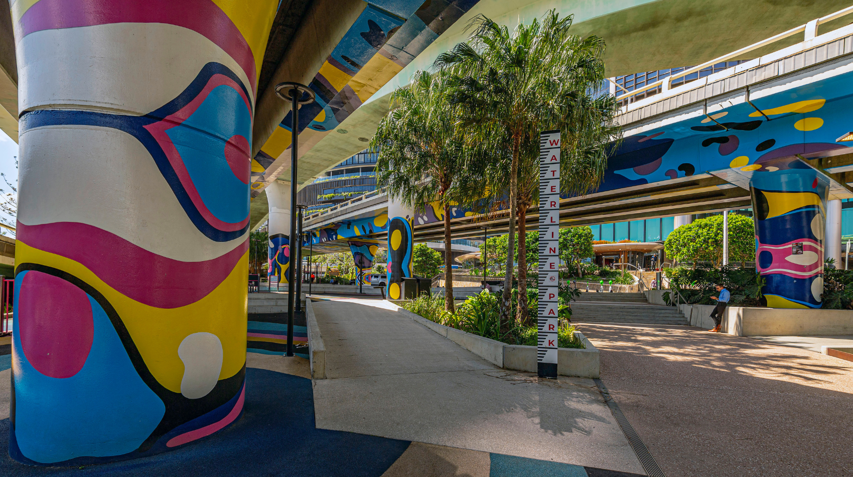 A colourful park and outdoor exercise area under bridges.